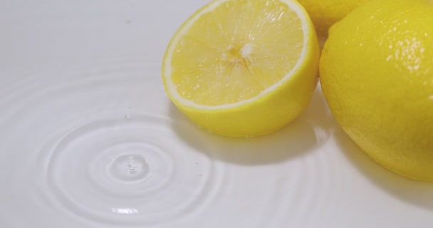 Gota caindo na água com limões, círculos divergentes. Citrões de citrinos naturais. Vitaminas, conceito de alimentação saudável — Vídeo de Stock