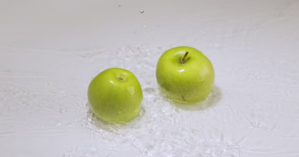 Gröna äpplen som rullar på vatten, slår till mot varandra. Naturliga frukter på studio bakgrund, vitaminer och hälsosam mat — Stockvideo