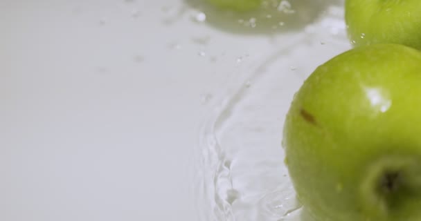 Zielone jabłka zderzają się ze sobą tocząc się na wodzie z rozbryzgami, naturalne owoce na białym tle, zdrowe odżywianie — Wideo stockowe