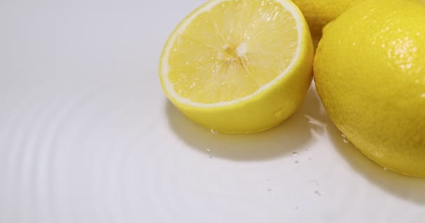 Limões que jazem na água, gotas que caem com círculos divergentes, cítricos naturais frescos. Vitamina alimentação saudável — Vídeo de Stock