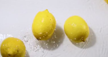 Suda yuvarlanan limonlar, beyaz stüdyo arka planında doğal meyve limonları, vitaminler ve sağlıklı beslenme konsepti, üst görünüm.