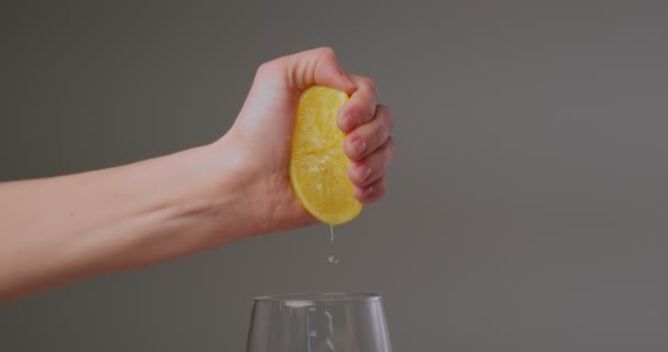 Main féminine presser le jus naturel frais du citron, gouttes tombant dans le verre. Vitamines et saine alimentation — Video