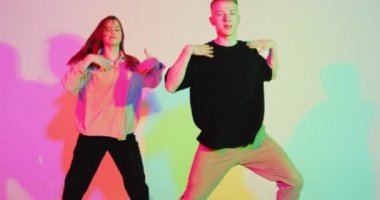Renkli neon renkli stüdyo ışığı altında dans eden genç bir çift. Çağdaş dans, hip hop dansçıları