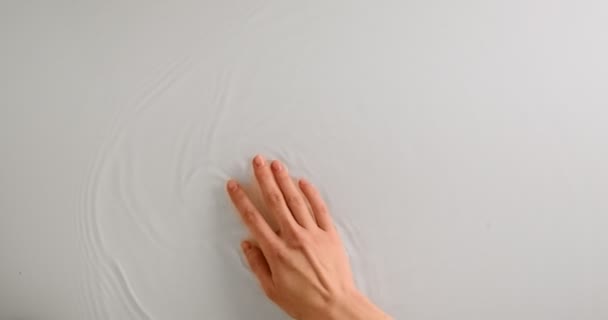 Vrouwelijke hand die zachtjes het wateroppervlak raakt. Bewegende arm stromend water, bovenaanzicht, kopieerruimte — Stockvideo