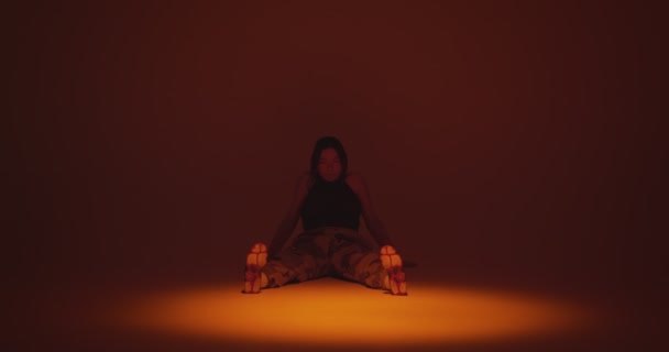 Девушка, сидящая, размахивая ногами на танцполе в центре внимания в студии. Отдыхаю или жду. Копирование пространства — стоковое видео