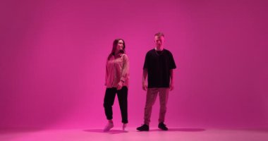 Pembe neon renkli stüdyo ışığında dans eden genç bir çift. Çağdaş dans, hip hop dansçılarının gösterisi