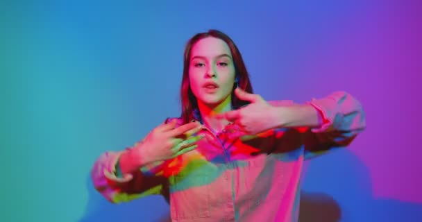 Tańcząca młoda dziewczyna cool poruszająca się w kolorowym neonowym świetle studio. Taniec współczesny, hip hop żeńska tancerka — Wideo stockowe