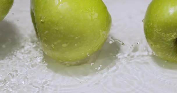 Zielone naturalne apetyczne jabłka uderzające o siebie toczące się w wodzie z rozbryzgami. Witaminy owocowe i zdrowe odżywianie — Wideo stockowe