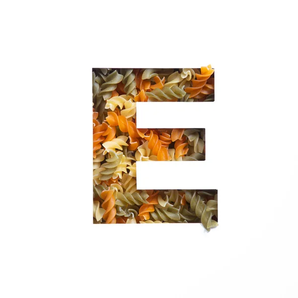 Italienisches Essen. Buchstabe E des englischen Alphabets aus Fusilli-Nudeln und weißem geschnittenem Papier. Schrift für die Gestaltung von Warenhäusern — Stockfoto