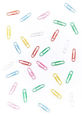 Beyaz arkaplana dağılmış renkli gökkuşağı ataçları. Evrak işleri için ataç. Ofis malzemeleri