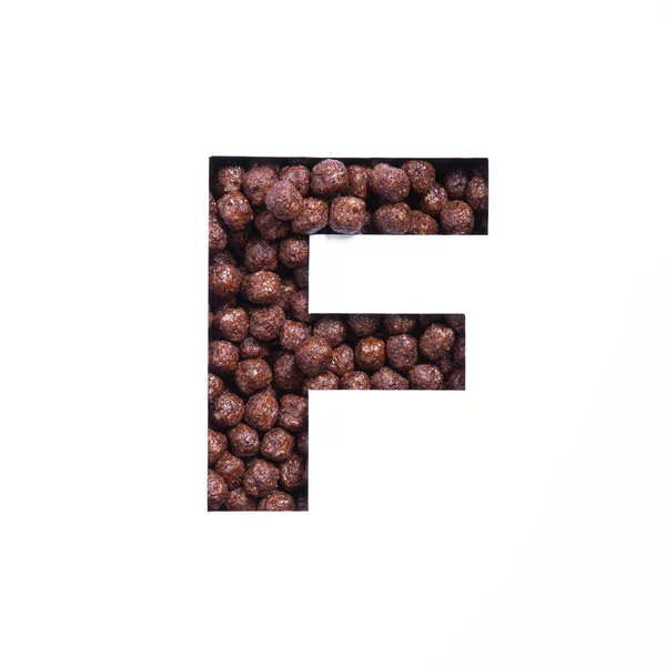 Letter F of English alphabet of nutritional chocolate cereal balls, white cut paper. Typeface for organic products store — Stock Photo, Image