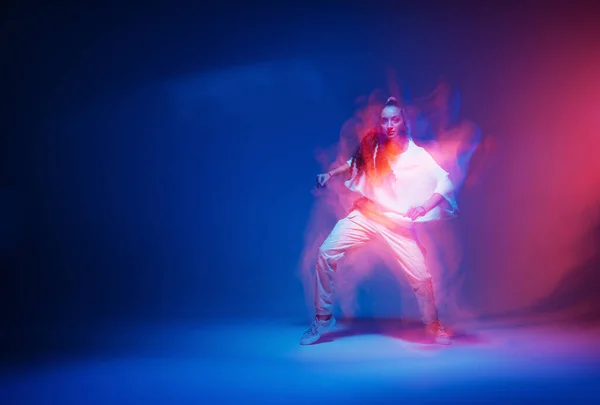 Stylowa tańcząca nowoczesna dziewczyna poruszająca się w kolorowym neonowym świetle studio. Długa ekspozycja. Przestrzeń kopiowania — Zdjęcie stockowe