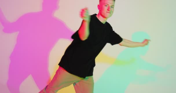 Menő, táncoló fiatal srác, színes neon stúdió fényben. Kortárs tánc, férfi hip-hop táncos. Rap ifjúsági kultúra — Stock videók