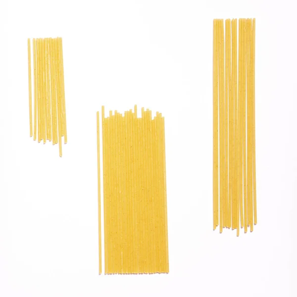 Espaguetis comida italiana sobre fondo blanco. Montones de vista superior de pasta sin cocer, fondo de pantalla elegante para el embalaje de productos —  Fotos de Stock