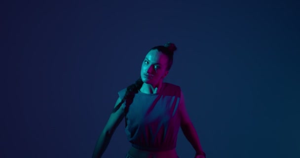 Cool ung blandras flicka dans etnisk afrikansk uttrycksfull dans eller hip-hop i neon studio ljus — Stockvideo