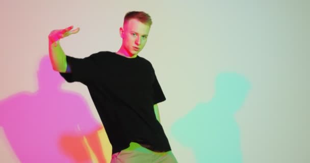 Energetische dansende jongeman bewegend in kleurrijk neon studio licht. Hedendaagse dans, hiphop mannelijke danser — Stockvideo