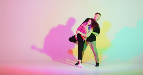 Danse jeune couple cool se déplaçant dans la lumière au néon coloré. Passionnée de danse contemporaine. Vidéo de publicité scolaire dansante — Video