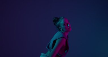 Neon Stüdyo ışığı altında ateşli ateşli dans eden havalı genç ırk kızı. Profesyonel kadın oyuncu.