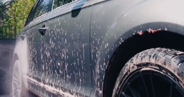 Araba yıkama ve oto yıkama servisi, yüksek basınçlı çamaşır makinesiyle arabayı köpükle kaplayan adam, videoyu kapat