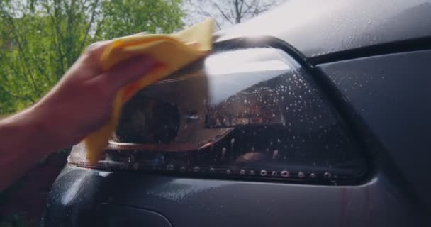 Nettoyage et essuyage par chiffon de projecteur dans le lavage de voiture. Phare avant masculin poli à la main. Concept de détail de voiture — Video