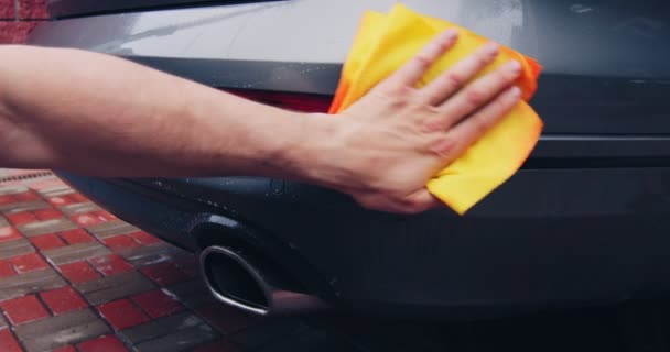 Férfi kézi dörzsölés autó felülete mikroszálas ruhával, autó fényszóró törlése védő feldolgozás után, mosás a garázsban — Stock videók
