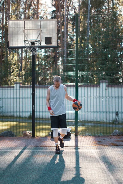 Jogador de basquete americano masculino profissional exercitando-se na quadra ao ar livre no verão na luz solar — Fotografia de Stock