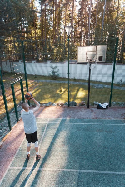 Jugador de baloncesto con entrenamiento de pelota en la cancha con el objetivo de aro de baloncesto al aire libre en verano en la naturaleza — Foto de Stock