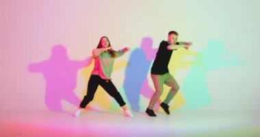 Dans eden genç çift renkli neon renkli stüdyo ışıklarıyla hareket ediyor. Çağdaş dans, hip hop dansçıları