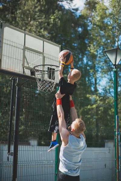 幸せな家族はバスケットボールをしている。息子を手にした若いスポーツの父。子供男の子投げボールでバスケットボールフープ — ストック写真