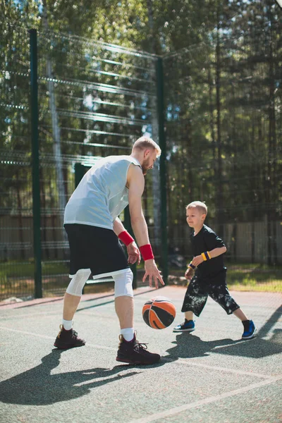 Profissional americano jogador de basquete instrutor treinar pouco esportes menino ao ar livre na quadra de basquete — Fotografia de Stock