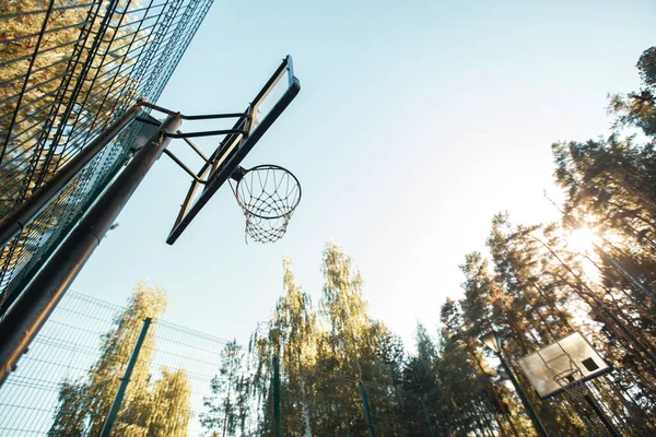 Баскетбольная площадка на природе. Баскетбольный обруч с сеткой на фоне летнего неба — стоковое фото