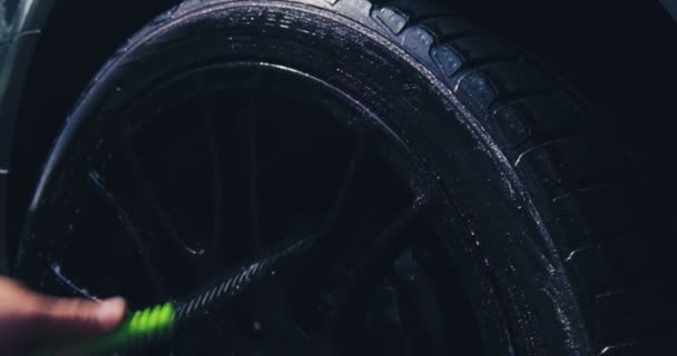 Arbetare med borste för rengöring av hjulytan vid biltvätt. Närbild av hjul rengöring. Detaljerat begrepp — Stockvideo