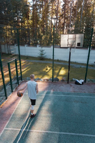 Profesional de baloncesto jugador de entrenamiento en la cancha al aire libre en verano en la naturaleza. Chico fresco con el ejercicio de pelota — Foto de Stock