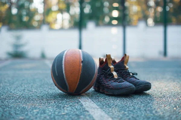 Basketball ball, sportive shoes for workout on basketball court, close up advertising photography in sunny day