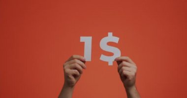 Hands showing one dollar, cost of purchase. 4k video of hand demonstrating cheap price made of carved paper for sale