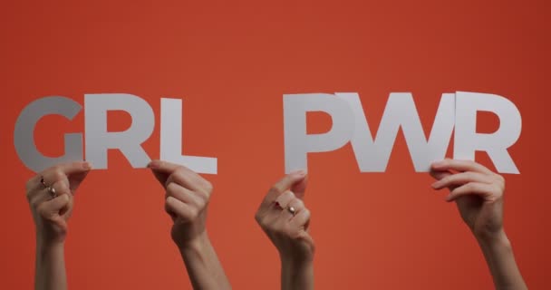 Hands raising up abbreviated slogan girl power. 4k video of arms showing feminism phrase made of carved paper — Stock Video