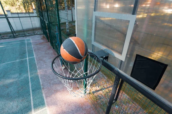 Balón de baloncesto volando en aro de baloncesto en la cancha al aire libre en verano en la naturaleza, vista superior. Concepto de meta — Foto de Stock