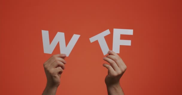 Ruce zobrazující písmena WTF anglického jazyka. Muž ukazuje vykřičník slang fráze vyřezávaného papíru pro blog — Stock video