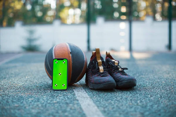 Maqueta de teléfono de pantalla verde con marcadores de seguimiento, pelota de baloncesto, zapatos deportivos. Smartphone Chroma key — Foto de Stock