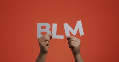 Siyahların hayatı önemlidir sloganı. Blog ekran koruyucusu için oyulmuş kağıttan yapılmış BLM harflerini gösteren eller yukarı.
