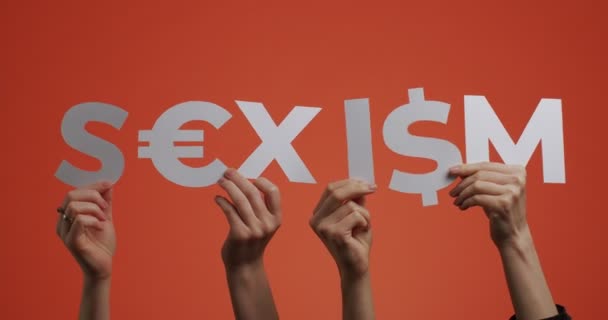 Mãos mostrando sexismo palavra de língua inglesa com euro, sinal de dólar. Palavra feita de papel esculpido para blog feminista — Vídeo de Stock