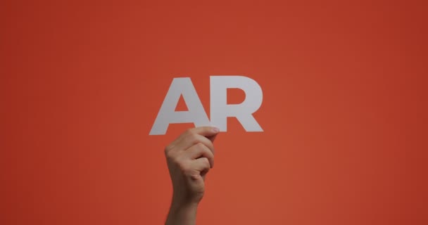 Mão levantando-se mostrando sinal de realidade aumentada. 4k vídeo de braço com letras ar feito de papel esculpido — Vídeo de Stock