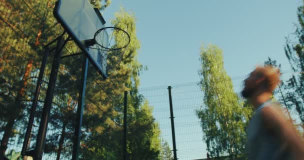 Professionele mannelijke amerikaanse basketbalspeler springen gooien bal in hoepel tijdens de training op het veld buiten. Doelstelling — Stockvideo