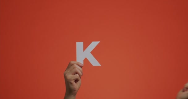 Руки, що показують слово "KO" з англійської мови. Чоловік показує знак нокауту зробленого з різьбленого паперу для блогу. — стокове відео