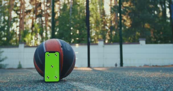 Maqueta de teléfono de pantalla verde con marcadores de seguimiento, pelota de baloncesto, zapatos deportivos lanzados al suelo. Smartphone Chroma key — Vídeos de Stock