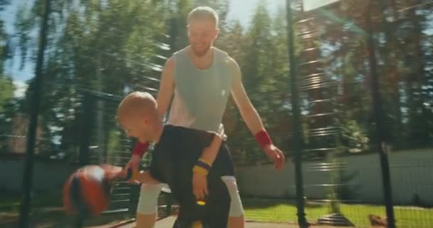 Entrenador de atletas estadounidenses y niño pequeño jugando al baloncesto al aire libre en la cancha de baloncesto — Vídeos de Stock