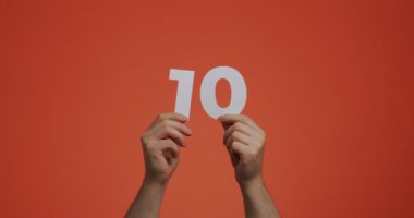 On numara ellerinde. Oy vermek ya da matematik öğrenmek için oylanmış kağıttan yapılmış 10 haneli rakamlar gösteren bir adam.