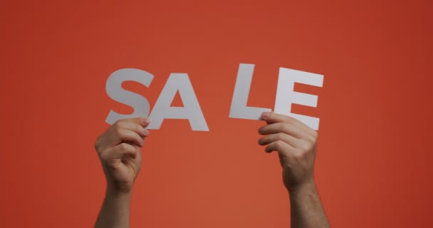 Продаж оголошення. Чоловік показує знак продажу на помаранчевій хроматиці. Зберігати пропозицію знижок. Концепція дешевих покупок — стокове відео