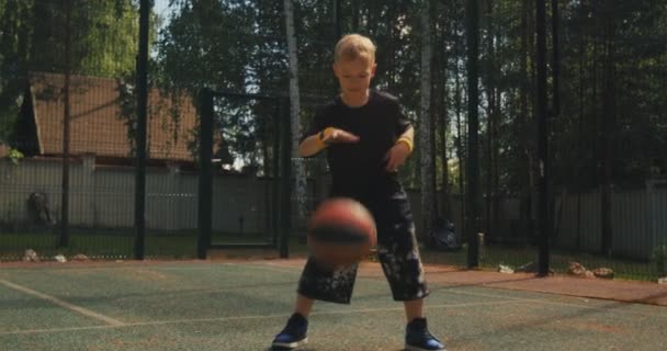 Enfant garçon joueur de basket-ball pratiquant la manipulation de balle sur le terrain de basket en plein air. Sport sain mode de vie des enfants — Video