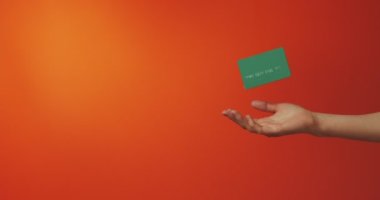 Turuncu arka planda izole edilmiş çevrimiçi hizmeti olan banka kredi kartı şablonu ile kadın elini kapat